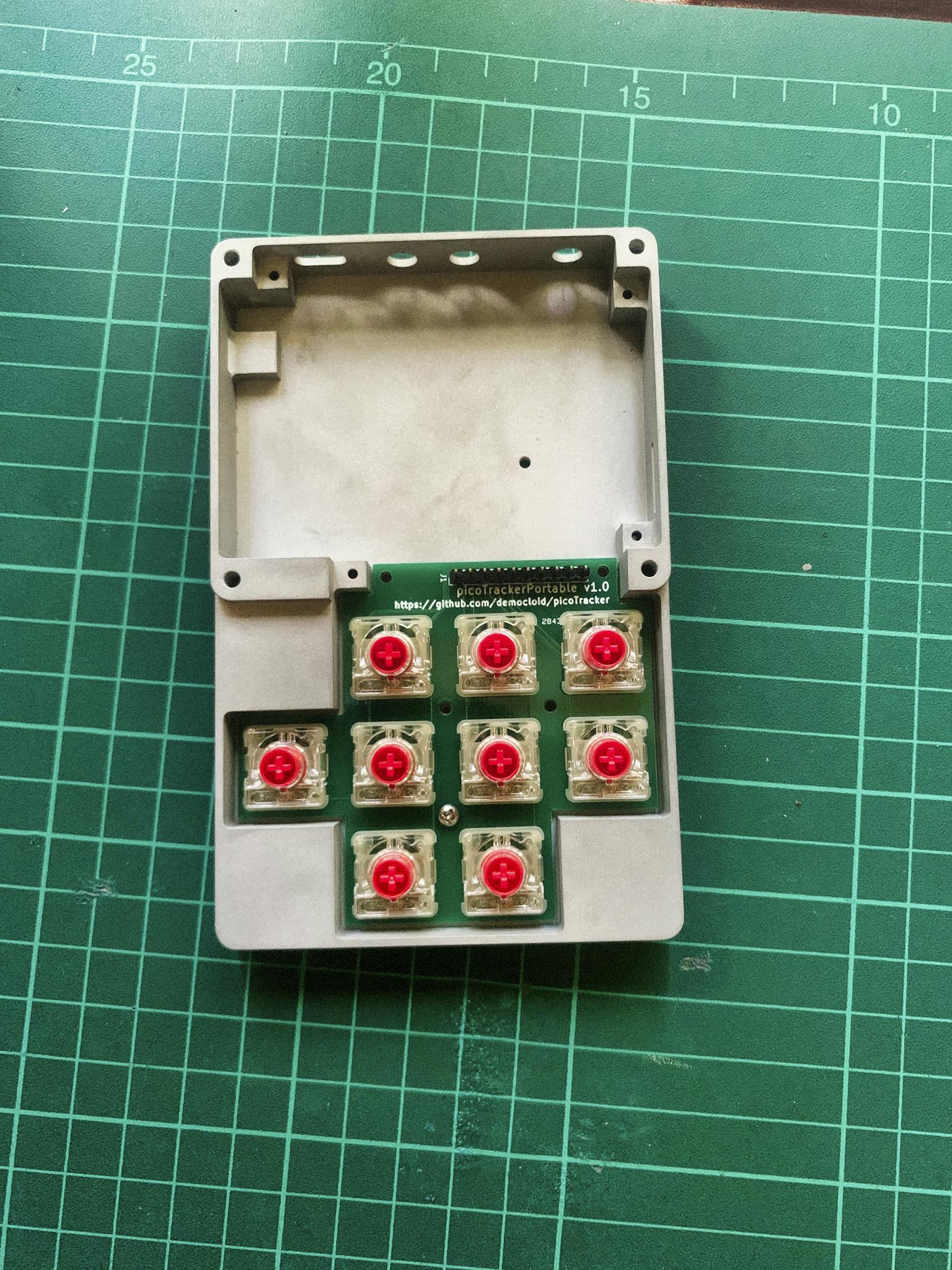 A DIY mechanical keypad circuit with red switches on a green cutting mat.